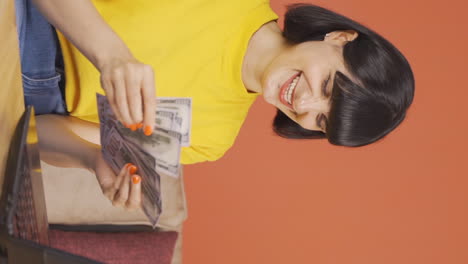 Vertical-video-of-Young-woman-looking-at-laptop-counting-money.